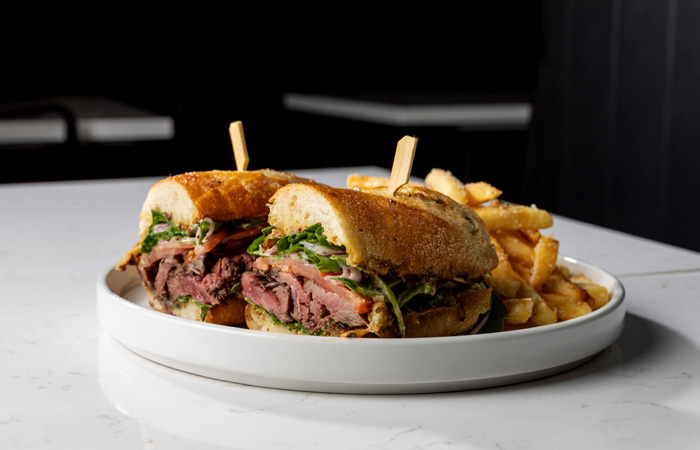  /></p>
<p>Now, Lincoln has a new concept. Dee’s Table Burgers & More sits a Dak Prescott deep ball away from Dee Lincoln’s Prime and offers a great casual sports bar atmosphere with simple, yet delicious, food, as well as some of Lincoln’s Louisiana flair sprinkled throughout the décor and on the menu.</p>
<p>This casual concept offers a great horseshoe-shaped bar which is perfect to relax, catch a game and a cold beverage as you check out the Dallas Cowboys’ memorabilia on the walls. As I entered, both the server for the bar tables and the bartender greeted me with a friendly “Welcome in!” There is also a separate seating area away from the bar, if you are just popping in for a quick lunch or business meeting with associates. A patio outside is a great spot for the spring months, with a nice open-air look at all the Cowboys’ monuments leading just up the street to the Ford Center.<span class=